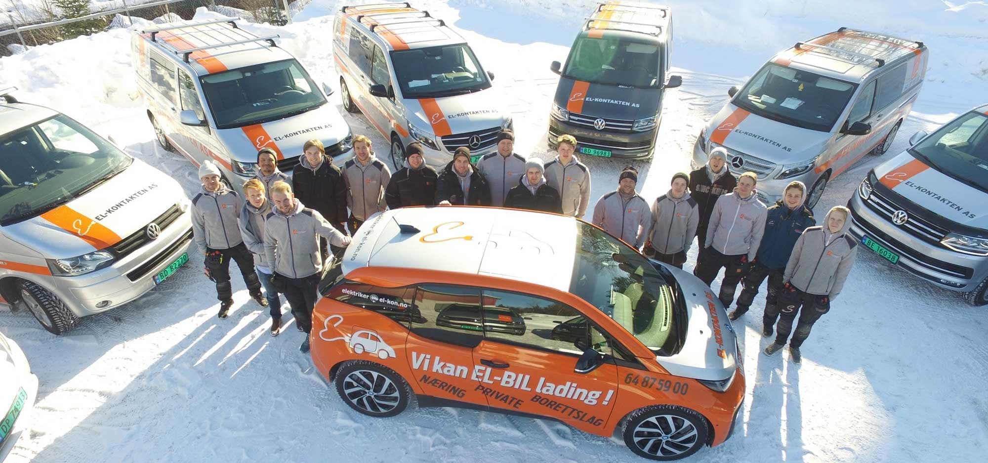 El-Kontakten-teamet samlet rundt firmabilene i snøen, med en oransje elbil merket «Vi kan EL-BIL lading!» foran.