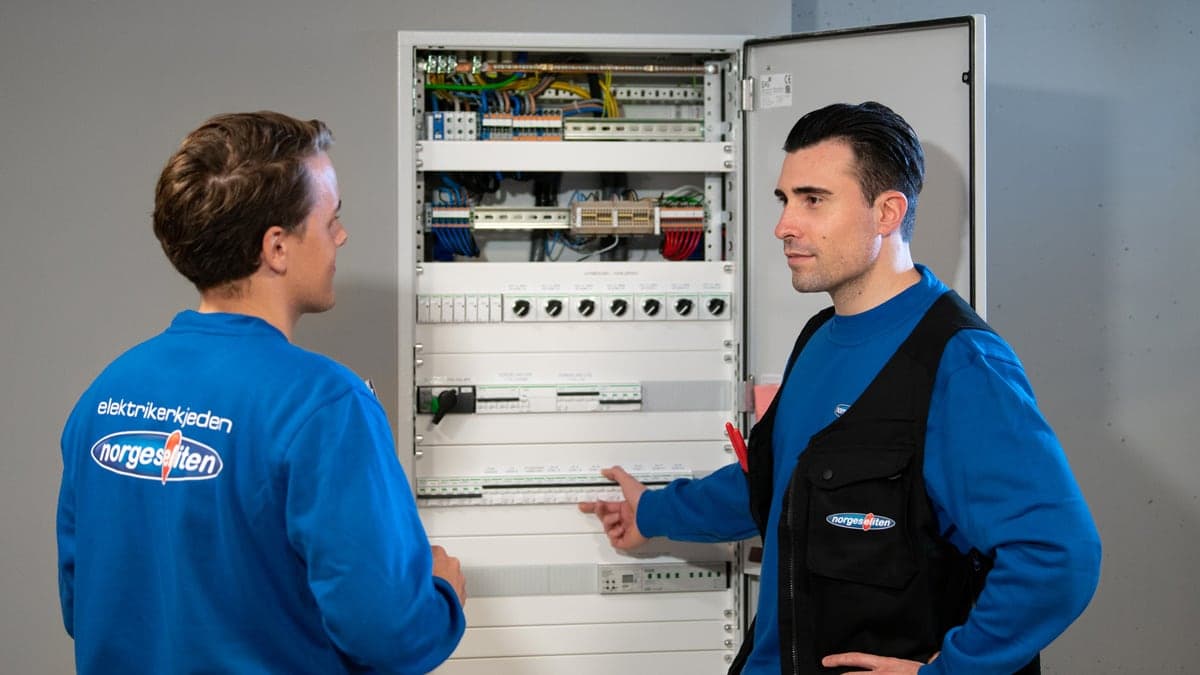 To elektrikere ved et åpent sikringsskap.
